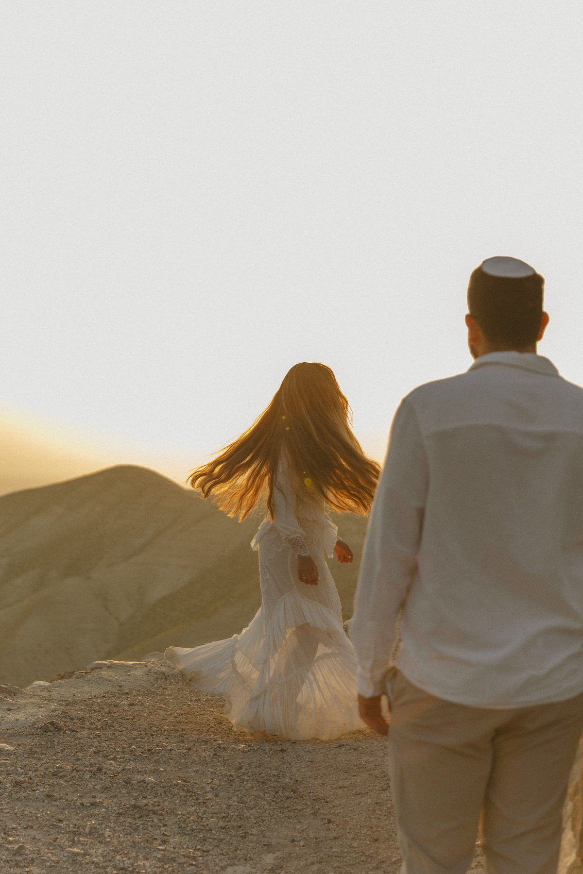 כלה מסובבת את השיער מול הרי המדבר בשקיעה